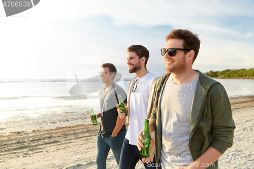 Image of young men with non alcoholic beer walking on beach