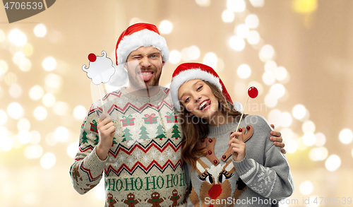 Image of couple with christmas party props in ugly sweaters