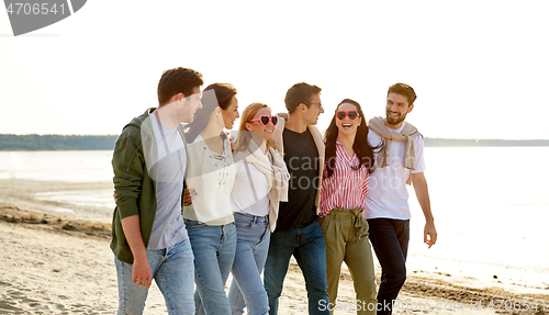 Image of happy friends walking along summer beach