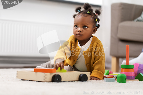 Image of african baby girl playing with toy blocks at home