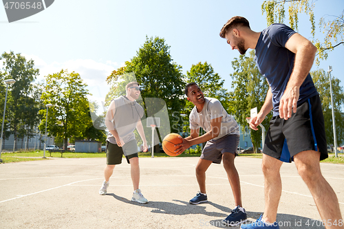 Image of group of male friends playing street basketball