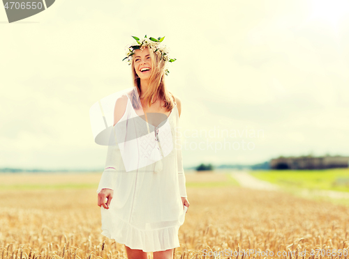 Image of happy young woman in flower wreath on cereal field