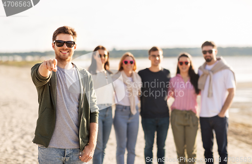 Image of happy man with friends on beach in summer