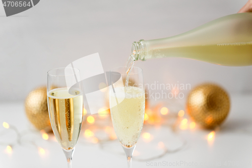 Image of champagne pouring from bottle to christmas glasses