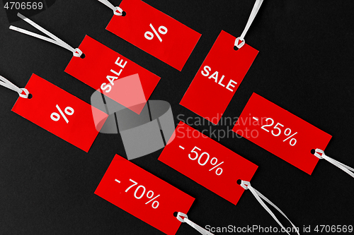 Image of red tags with discount signs on black background