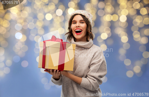 Image of young woman in winter hat holding christmas gift