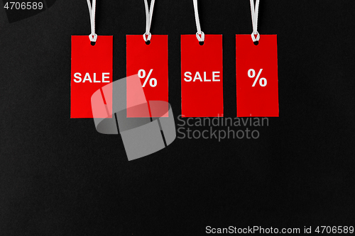 Image of red tags with discount signs on black background