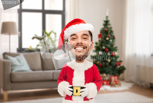 Image of smiling man in santa costume over christmas tree