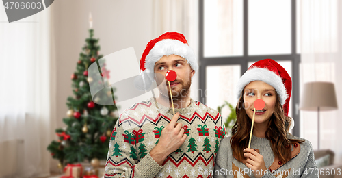 Image of couple with christmas party props in ugly sweaters