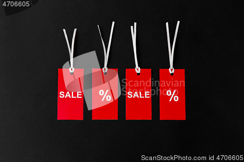 Image of red tags with discount signs on black background