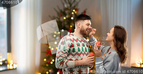 Image of couple with cupcakes in ugly christmas sweaters