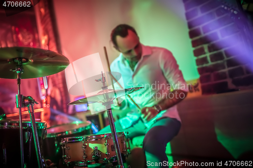 Image of Drummer playing on drum set on stage.