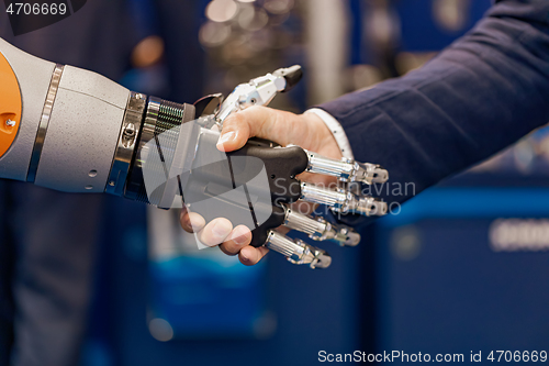 Image of Hand of a businessman shaking hands with a Android robot.