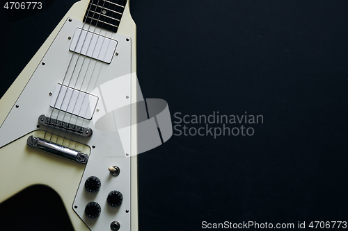 Image of White V shape electric guitar on dark grunge background.