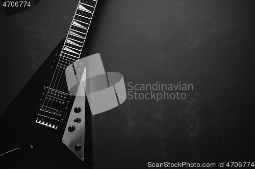 Image of Black V shape electric guitar on dark grunge background.