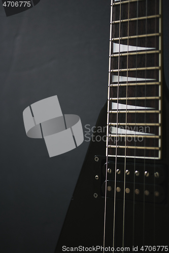 Image of Black V shape electric guitar on dark grunge background.