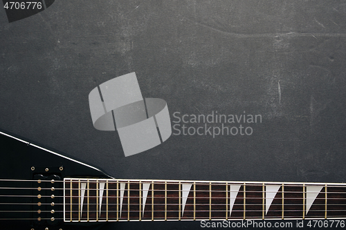 Image of Black V shape electric guitar on dark grunge background.