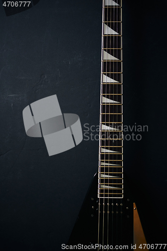 Image of Black V shape electric guitar on dark grunge background.