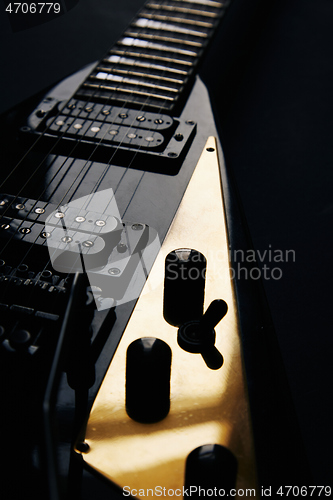 Image of Black V shape electric guitar on dark grunge background.