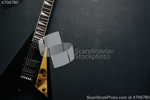 Image of Black V shape electric guitar on dark grunge background.