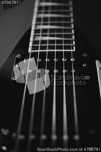 Image of Black V shape electric guitar on dark grunge background.