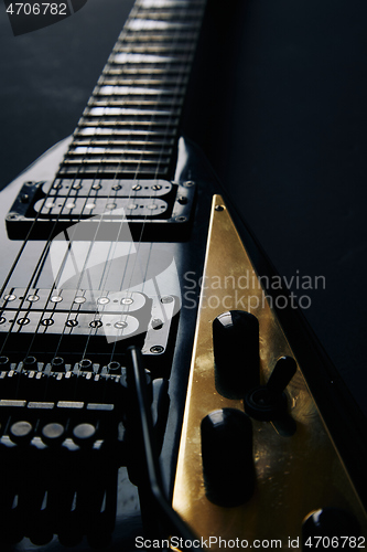 Image of Black V shape electric guitar on dark grunge background.