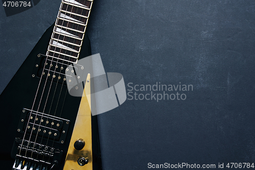 Image of Black V shape electric guitar on dark grunge background.