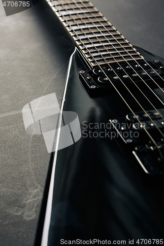 Image of Black V shape electric guitar on dark grunge background.