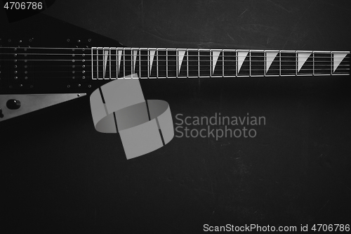 Image of Black V shape electric guitar on dark grunge background.