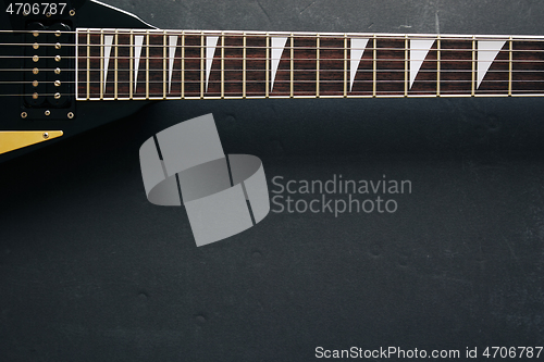 Image of Black V shape electric guitar on dark grunge background.