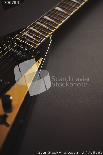 Image of Black V shape electric guitar on dark grunge background.