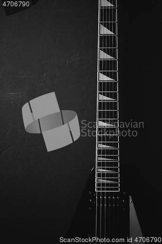 Image of Black V shape electric guitar on dark grunge background.