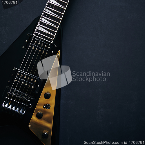 Image of Black V shape electric guitar on dark grunge background.