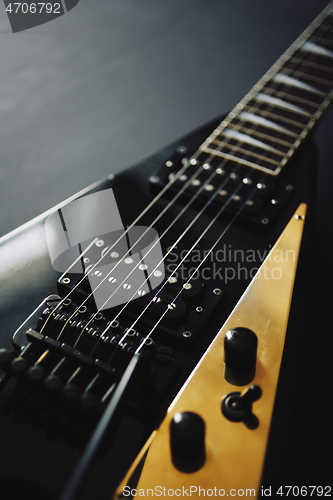 Image of Black V shape electric guitar on dark grunge background.