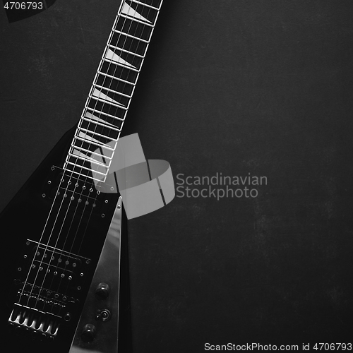 Image of Black V shape electric guitar on dark grunge background.