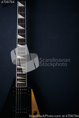 Image of Black V shape electric guitar on dark grunge background.