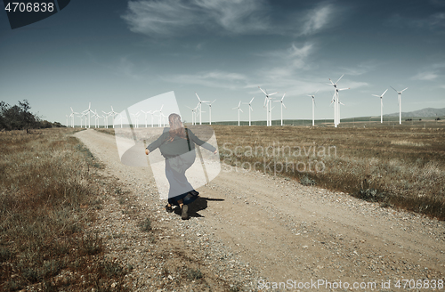 Image of Woman with long tousled hair next to the wind turbine with the w