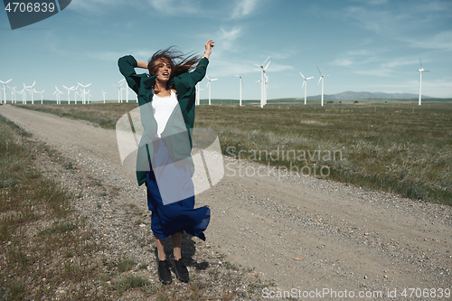 Image of Woman with long tousled hair next to the wind turbine with the w