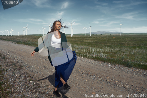 Image of Woman with long tousled hair next to the wind turbine with the w