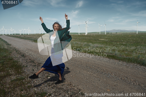 Image of Woman with long tousled hair next to the wind turbine with the w