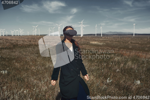 Image of Woman wearing VR headset at the field next to the wind turbines