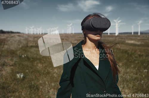 Image of Woman wearing VR headset at the field next to the wind turbines