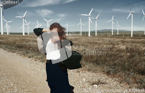 Image of Woman with long tousled hair next to the wind turbine with the w