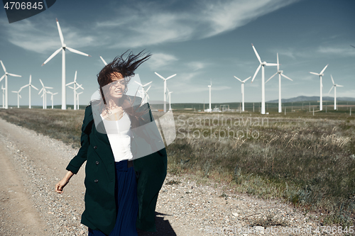 Image of Woman with long tousled hair next to the wind turbine with the w