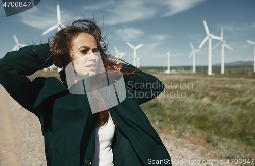 Image of Woman with long tousled hair next to the wind turbine with the w