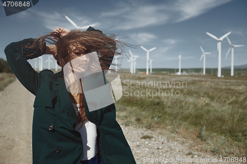 Image of Woman with long tousled hair next to the wind turbine with the w