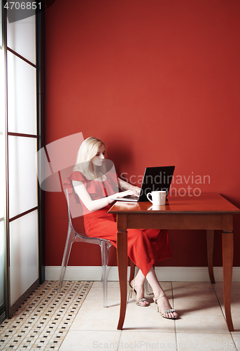 Image of Beautiful young adult woman wearing red jumpsuit and working lap