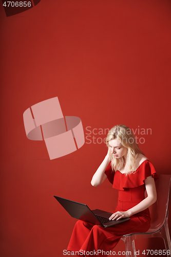 Image of Young adult woman sitting on a chair and working on laptop