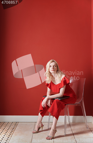 Image of Young adult woman sitting on a chair and holding laptop