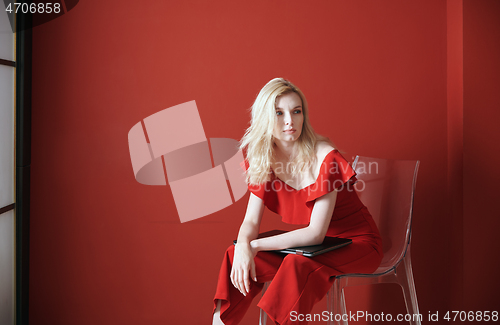 Image of Young adult woman sitting on a chair and holding laptop